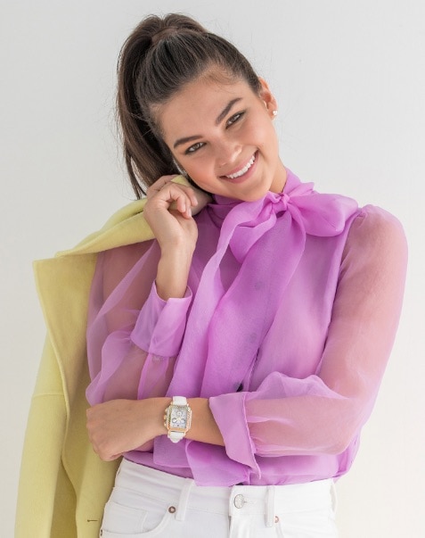 Young woman wearing fashionable and colorful top with the Deco watch featuring a rainbow of sparkling topaz stones along the bezel and bright white leather strap.